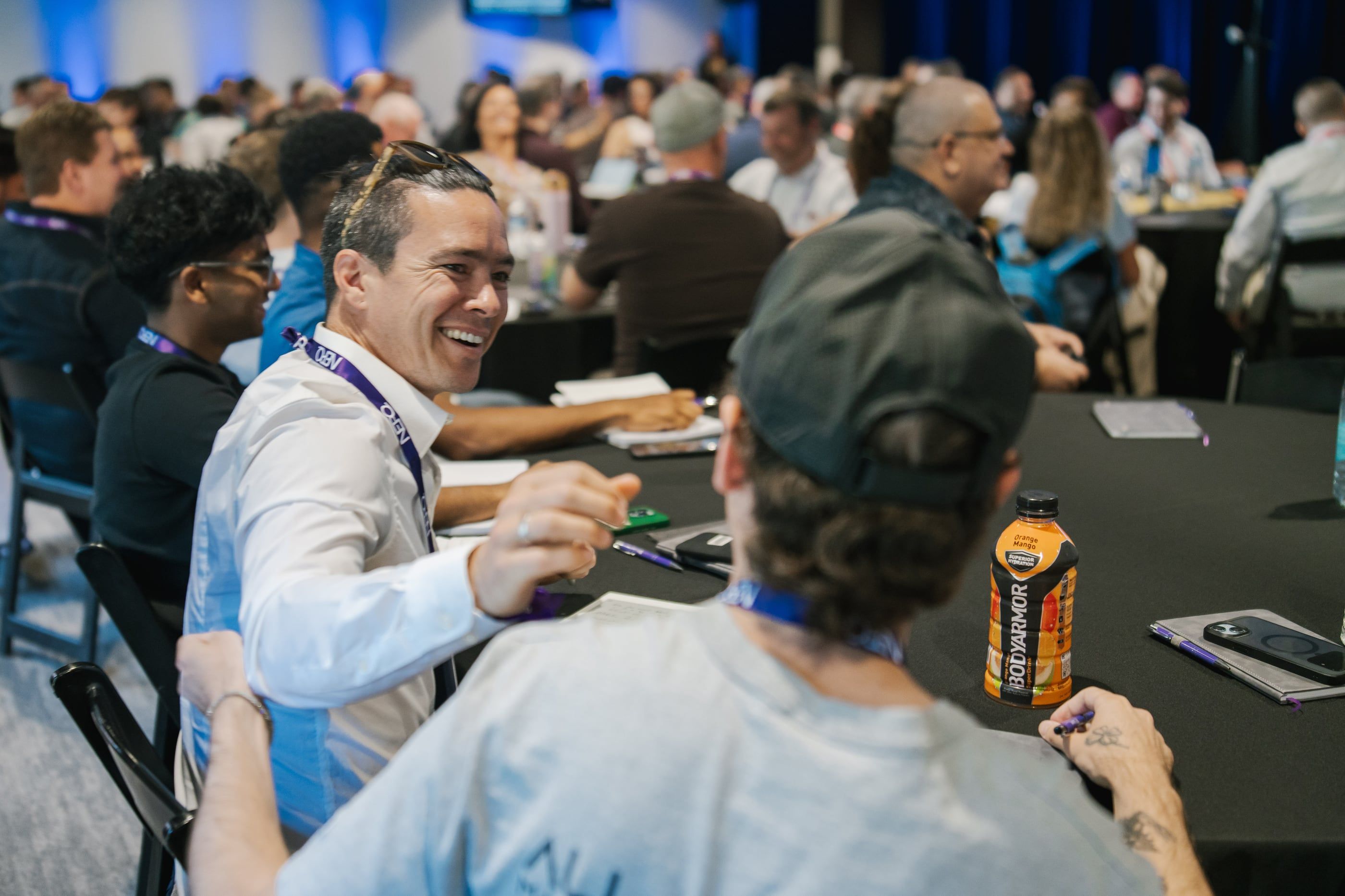 An attendee laughing with the person beside him at a summit table